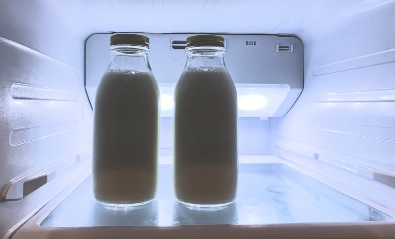 Photo of a refrigerator shelf with two glass bottles of milk.