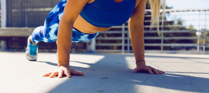 Exercise motivation. Photo of a woman in blue and white leggings and a bright blue crop top doing a push up.