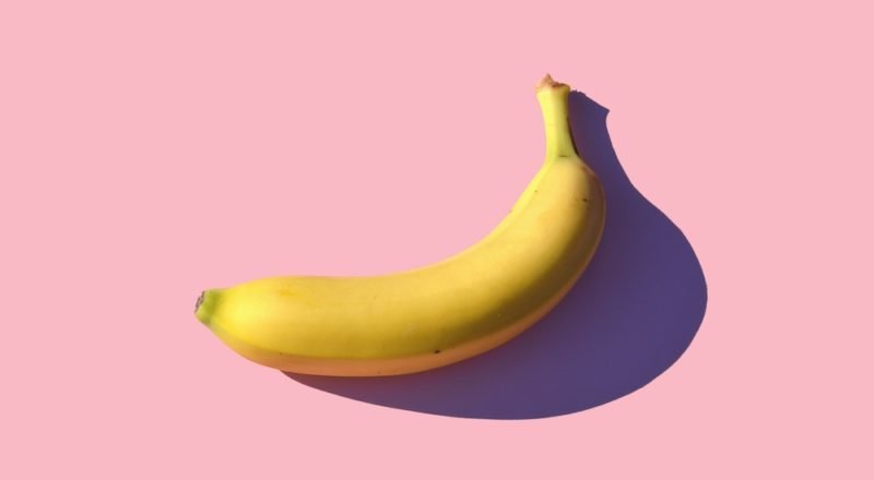Photo of a banana on a pink background.