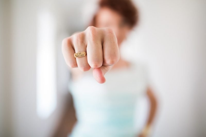 I take nutrition myth-busting seriously. Photo is a blurry image of a woman with her fist extended towards the camera (in focus), with a gold ring that says "I am bad ass."