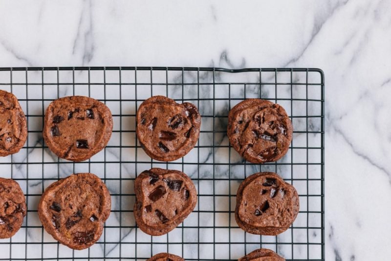 A cooling rack of chocolate chunk cookies on a marble countertop. When you enjoy food freedom, you can take or leave cookies, enjoying them without guilt.