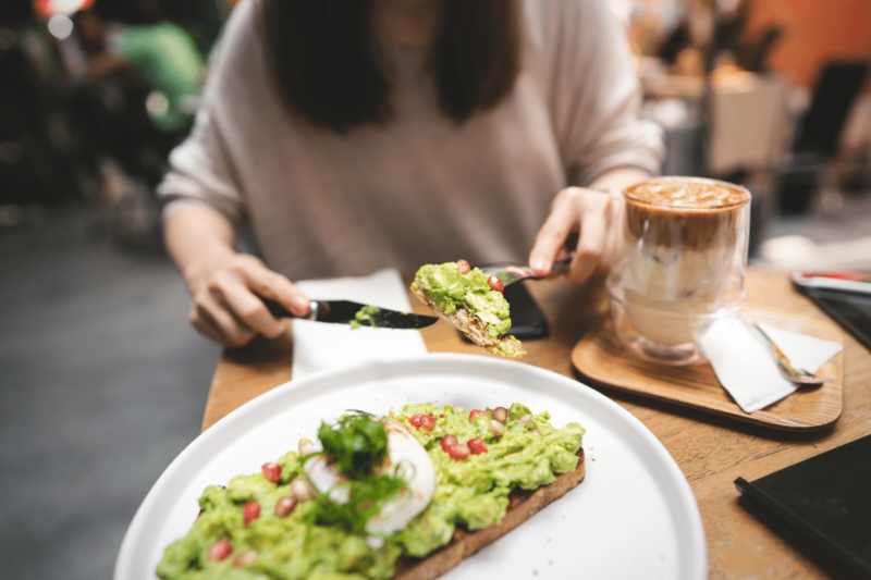 Woman eating avocado toast in a restaurant.