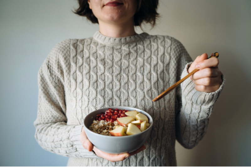 Woman eating a breakfast bowl with grains, fruit and yogurt