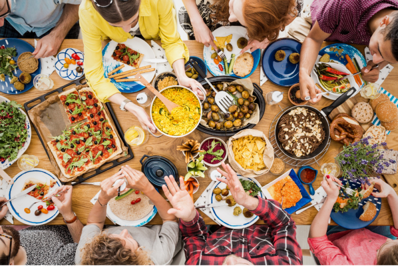 Overhead view of friends enjoying a meal at a table holding a variety of foods