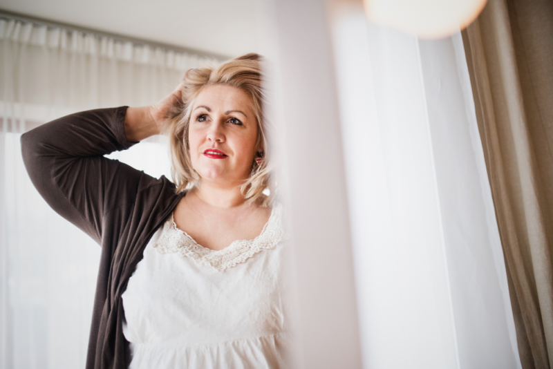 Woman in plus size body looking at herself in the mirror.